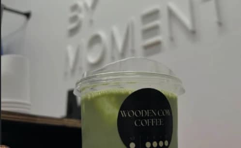 A branded iced matcha in front of a client's dimensional wall sign at a studio activation