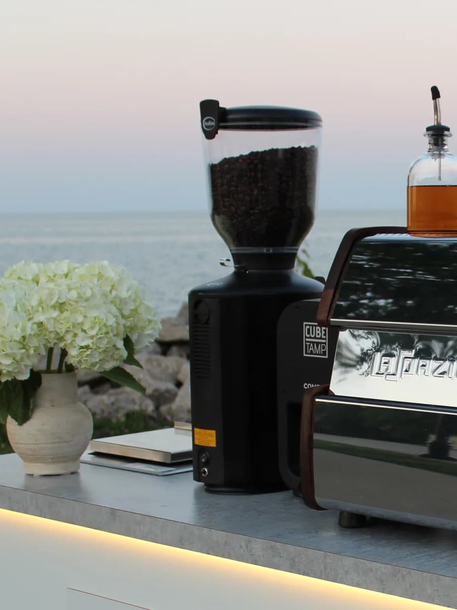 White hydrangeas beside the grinder and espresso machine on the cart counter, Lake Michigan behind