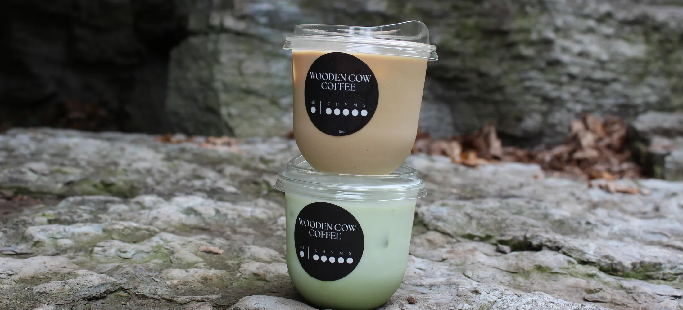 An iced caramel latte stacked on an iced matcha latte on limestone