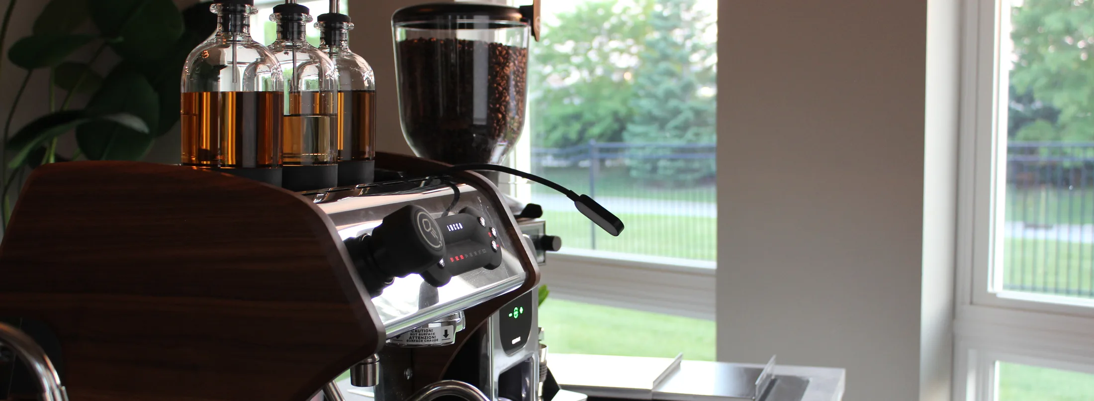 Syrup bottles, grinder and espresso machine set up in a bright daylight interior