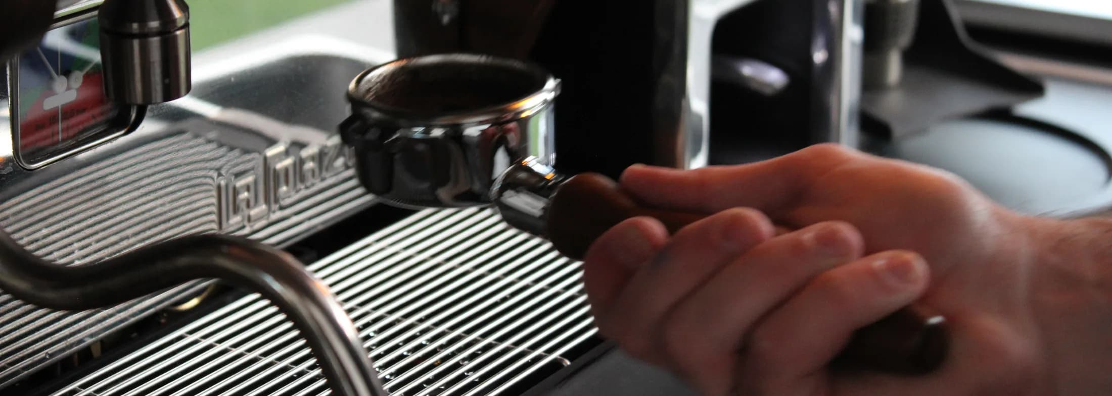 A hand locking the portafilter into the espresso machine group head